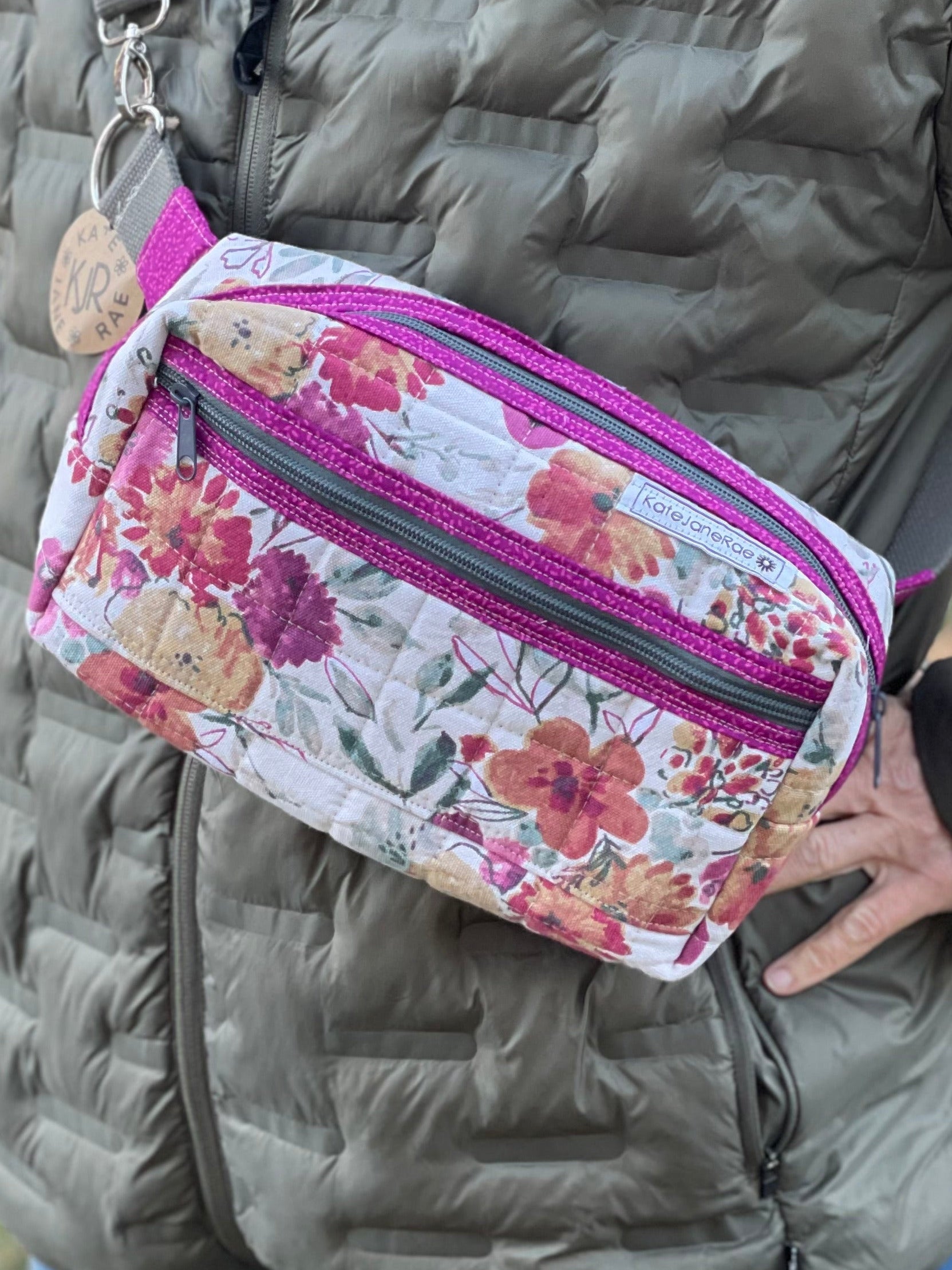Person wearing a floral fanny pack with a lake and trees in the background