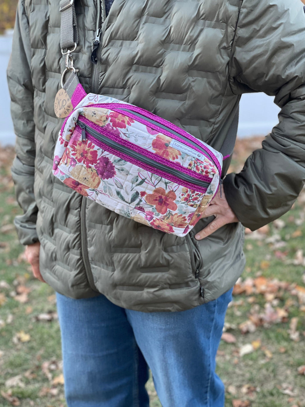 Person wearing a floral fanny pack with a pink zipper outdoors.
