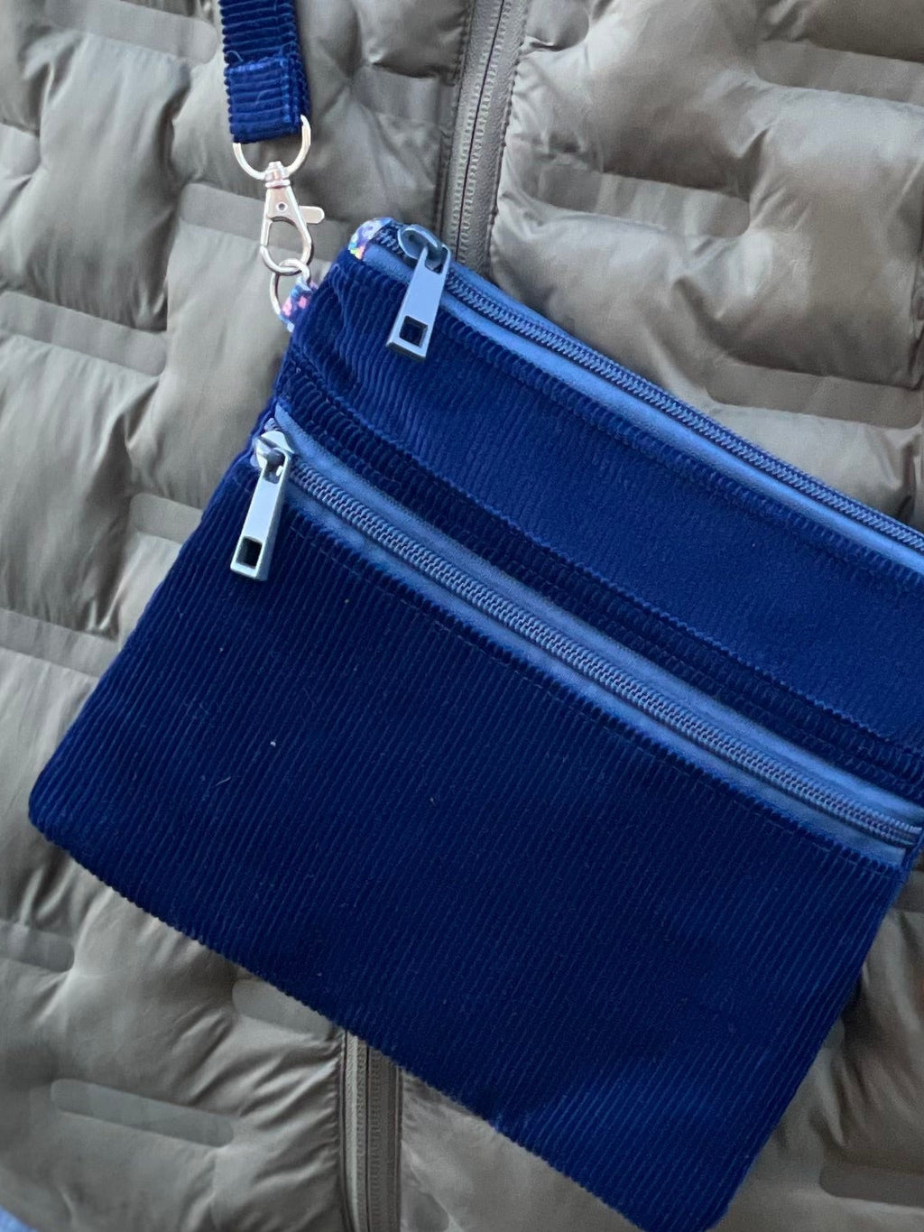 Person wearing a gray puffer jacket with a blue crossbody bag outdoors.