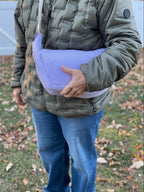 Person holding a purple checkered bag outdoors on a grassy area.