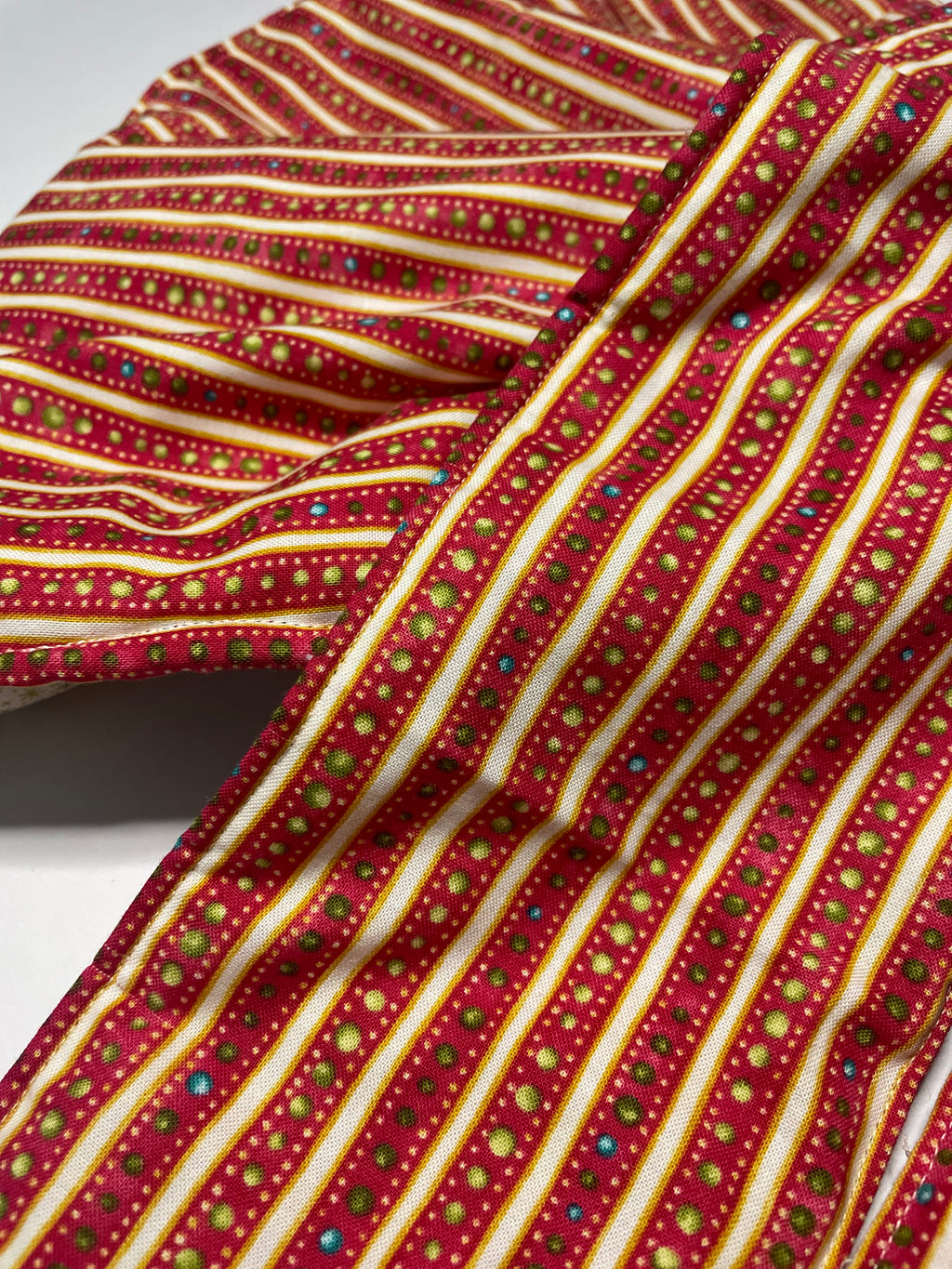 Close-up of a red and gold striped fabric with small multicolored dots.