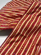 Close-up of a red and gold striped fabric with small multicolored dots.