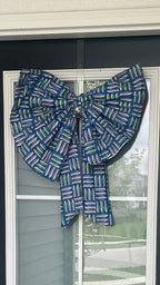 Black front door with a decorative blue bow and 'No Soliciting' sign, featuring a glass panel.