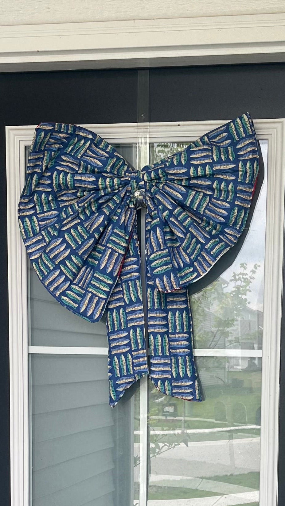Black front door with a decorative blue bow and 'No Soliciting' sign, featuring a glass panel.