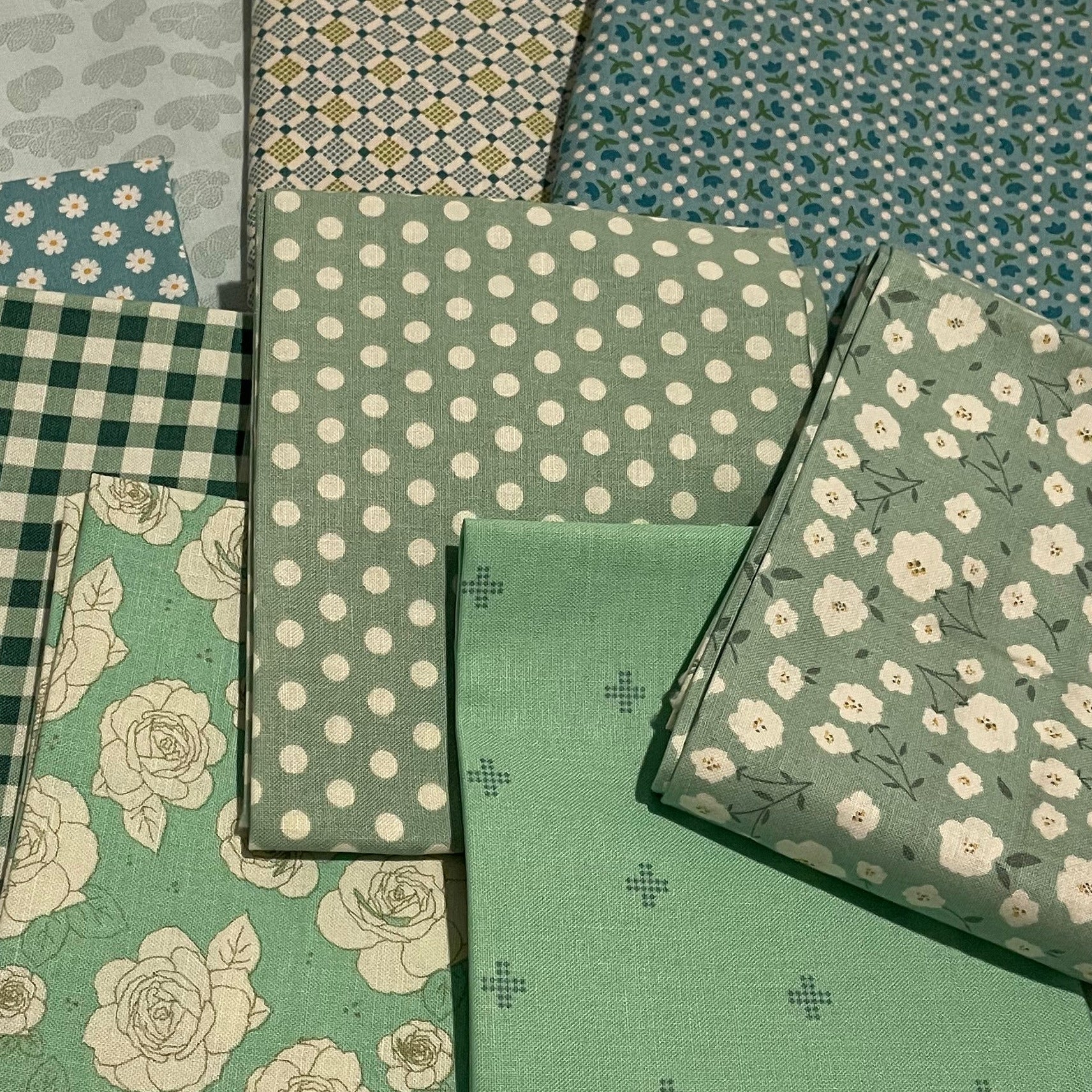 Collection of green fabric samples with various patterns on a beige background