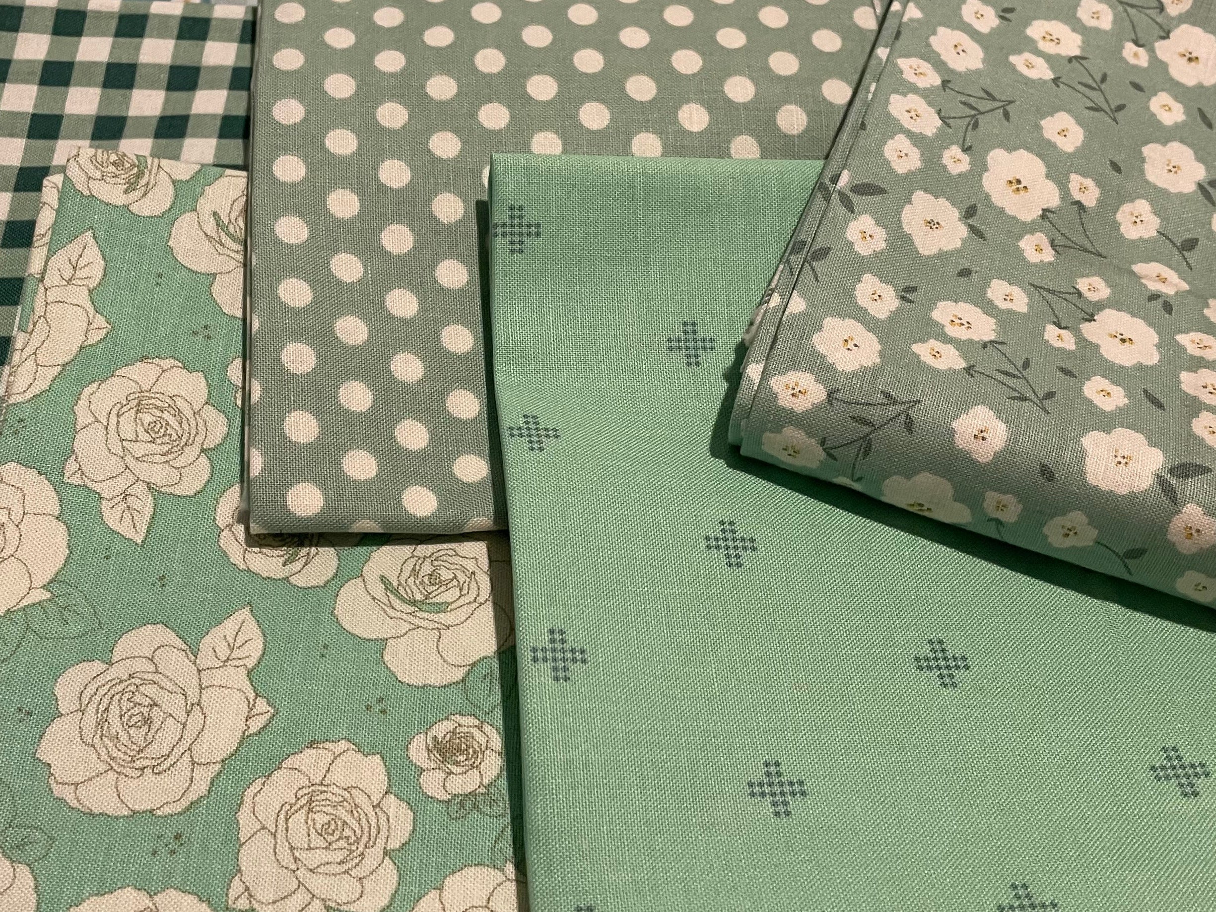 Collection of green and blue patterned fabric swatches on a light background
