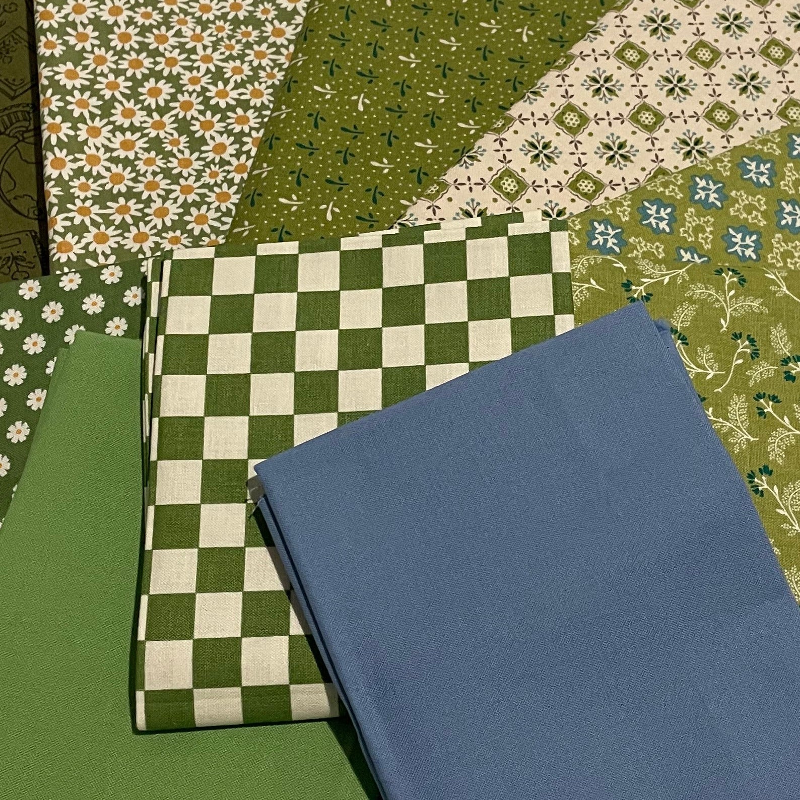 Collection of green patterned fabric squares on a beige background