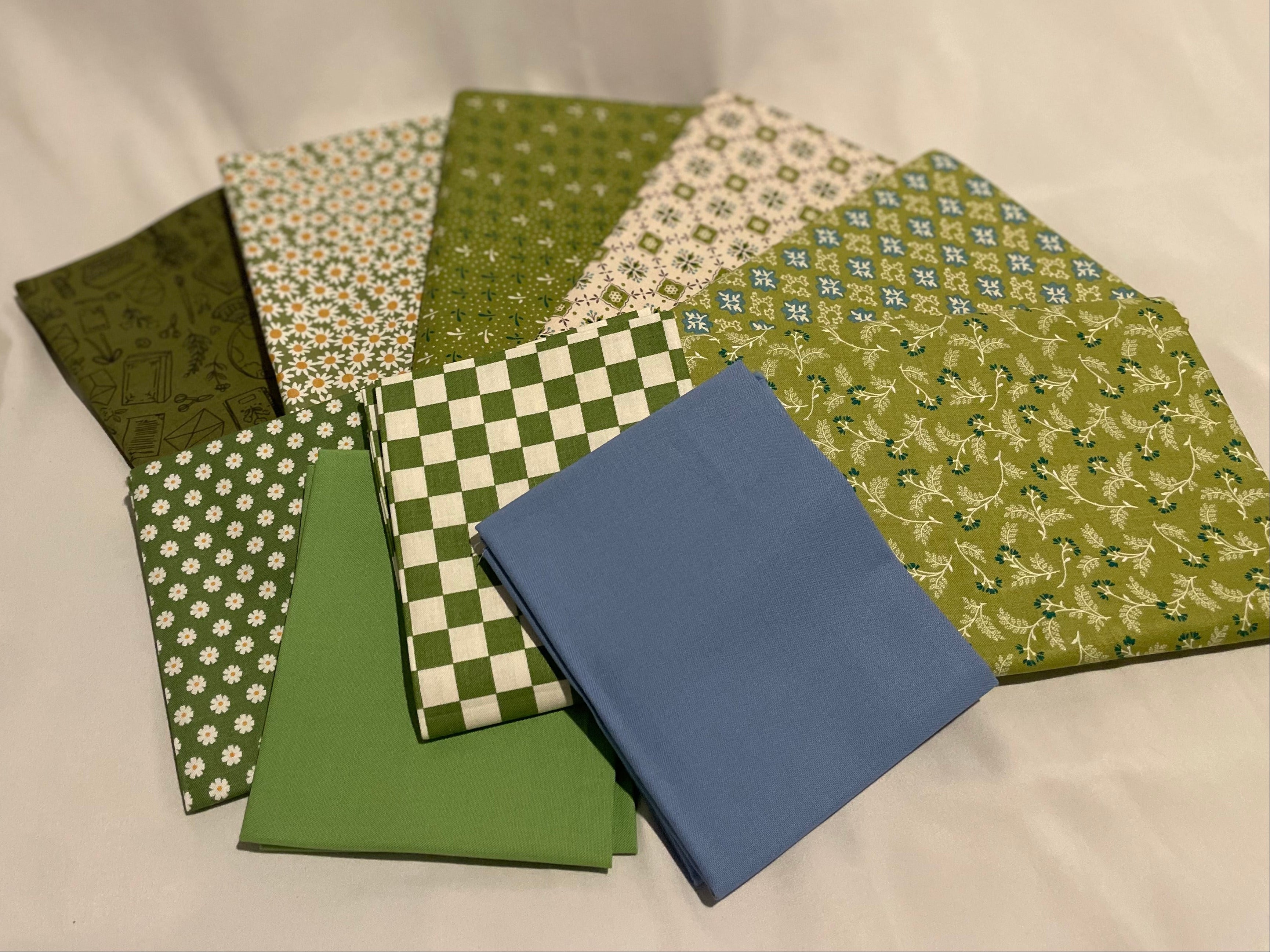 Collection of green fabric squares with various patterns on a white background