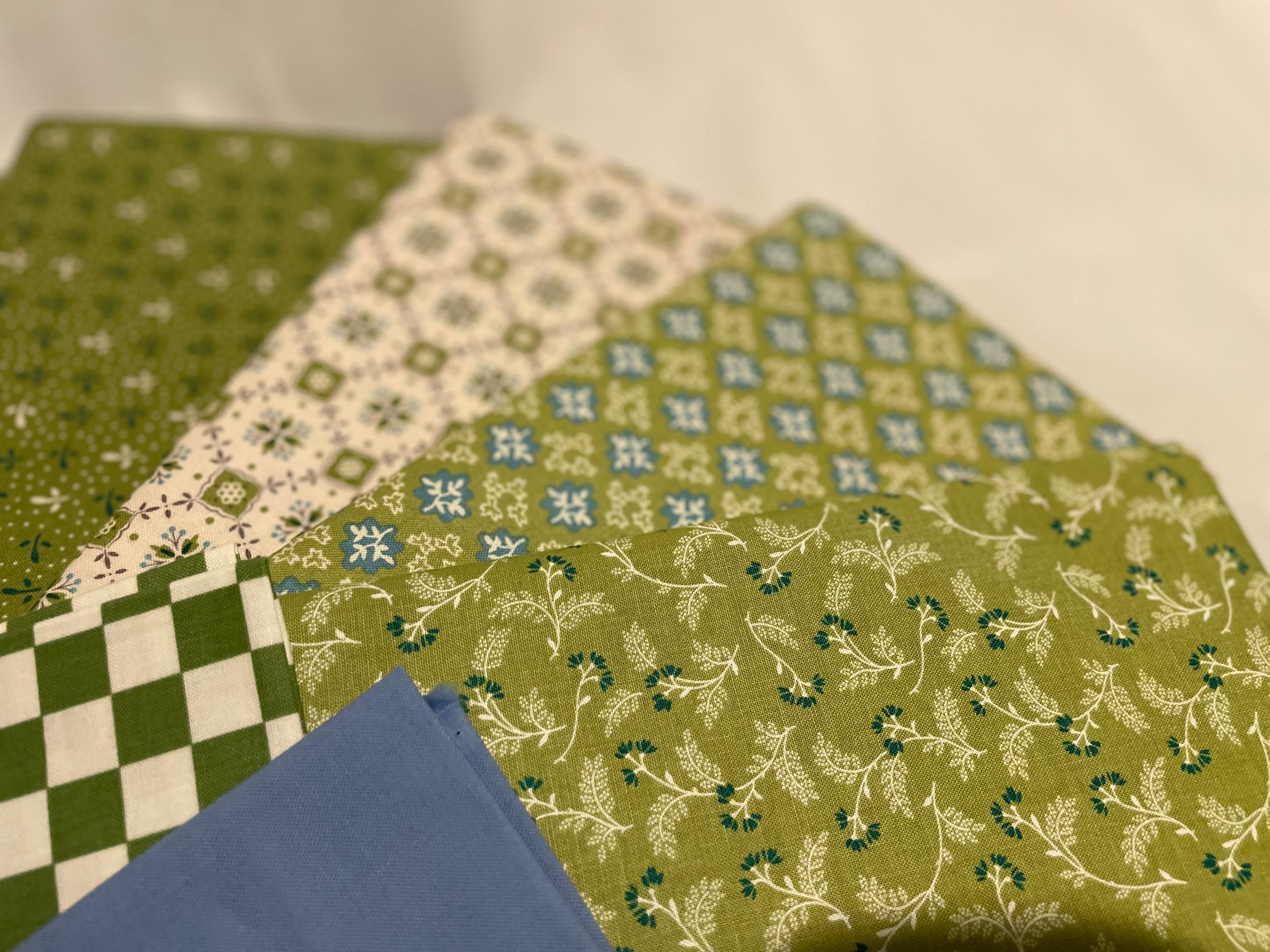 Collection of green and blue patterned fabrics on a neutral background