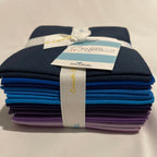 Set of folded fabric swatches in blue and purple with a label on a beige background