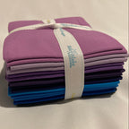 Set of colorful fabric strips bundled together with a band on a beige background