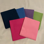 Five colorful notebooks arranged on a beige surface.