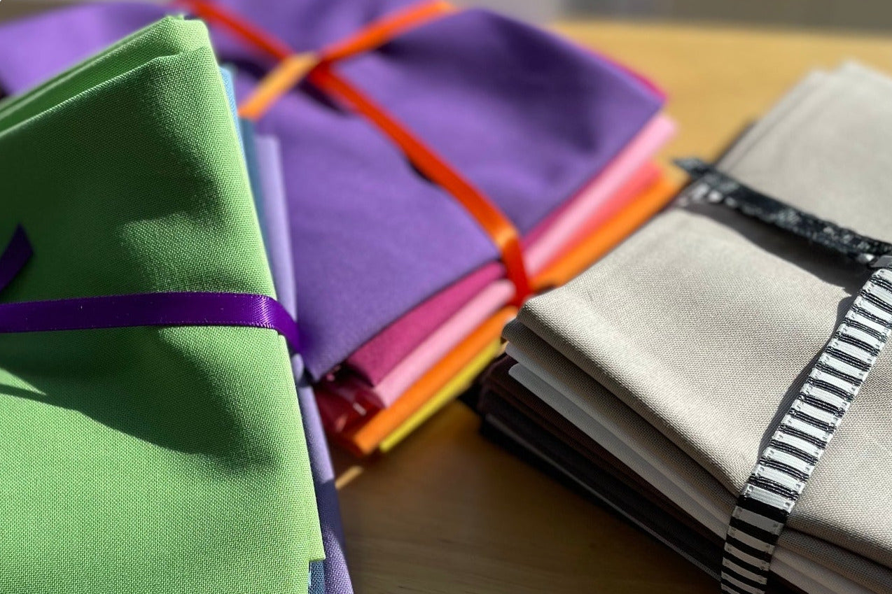 Colorful folded cloths tied with ribbons on a wooden surface