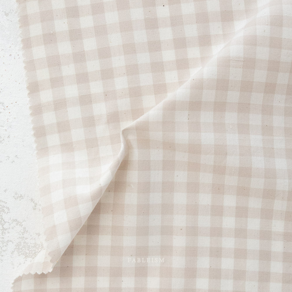 Close-up of beige and white checkered fabric with a visible brand name.